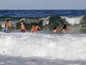 Swimmers dive into a wave at Seabrook Beach, Monday, Aug. 20, 2018, in Seabrook, N.H. Authorities in New Hampshire say two swimmers caught in riptides on Sunday have died. Rip currents, sometimes referred to as riptides, are narrow channels of water that move as fast as 8 feet a second and occur at any beach with breaking waves. Anyone caught in them is advised to swim parallel to shore to escape their pull.