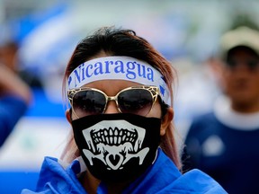 A masked woman takes part in an anti-Ortega march by university students and medical doctors dismissed from public hospitals for treating wounded anti-government protesters, in Managua, Nicaragua, on July 31, 2018.