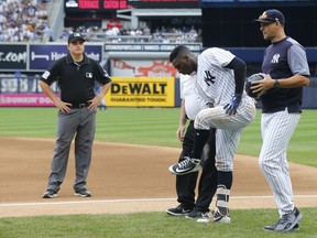 New York Yankees trainer Steve Donohue, third from right, and manager Aaron Boone, right, check on Didi Gregorius, second from right, after a collision with Toronto Blue Jays first baseman Kendrys Morales (not shown) in the first inning of a baseball game in New Yorkm, Sunday, Aug. 19, 2018.