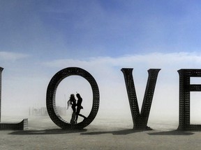 In this Aug. 30, 2014 photo, a couple stands inside a love sculpture at Burning Man on the Black Rock Desert of Gerlach, Nev. The #MeToo movement is making its way to Burning Man which begins Aug. 26-Sept. 3, 2018. Organizers are reminding attendees that just because the counterculture festival in the Nevada desert is known for occasional nudity and kinky landmarks like the "Orgy Dome," it doesn't mean it's a free-for-all when it comes to touching or non-consensual sex.