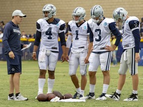 FILE - In this Saturday, July 28, 2018, file photo, Dallas Cowboys quarterback coach Kellen Moore, left talks to quarterbacks Dak Prescott (4), Dalton Sturm (1), Mike White (3) and Cooper Rush, far right, during NFL football training camp in Oxnard, Calif. In one year, Moore has gone from sitting next to Dak Prescott in meetings to running them as the new quarterbacks coach of the Cowboys.