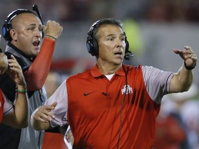 FILE - In this Sept. 17, 2016, file photo, Ohio State head coach Urban Meyer, right, and then-assistant coach Zach Smith, left, gesture from the sidelines during an NCAA college football game against Oklahoma in Norman, Okla. Ohio State expects to open fall camp as scheduled on Friday, Aug. 3, 2018, but without coach Urban Meyer.  Meyer was put on administrative leave on Wednesday, Aug. 1 over the handling of a longtime assistant who has been accused of domestic violence. Co-offensive coordinator Ryan Day will be running the team while Ohio State investigates claims that Meyer's wife knew about 2015 allegations of abuse against former Buckeyes assistant Zach Smith, who was fired last week.