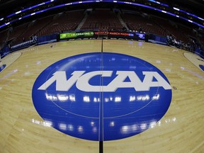 FILE - In this March 21, 2013, file photo, taken with a fisheye lens, the NCAA logo is displayed on the court during the NCAA college basketball tournament in Philadelphia. College basketball players who go undrafted by the NBA will be allowed to return to school and play as part of sweeping NCAA reforms in the wake of a corruption scandal, the NCAA announced Wednesday, Aug. 8, 2018.