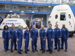 This undated photo made available by NASA on Friday, Aug. 3, 2018 shows, from left, Sunita Williams, Josh Cassada, Eric Boe, Nicole Mann, Christopher Ferguson, Douglas Hurley, Robert Behnken, Michael Hopkins and Victor Glover standing in front of Boeing's CST-100 Starliner and SpaceX's Crew Dragon capsules at the Kennedy Space Center in Florida. On Friday, the space agency announced the astronauts who will ride the first commercial capsules into orbit next year and bring human launches back to the U.S. (NASA via AP)