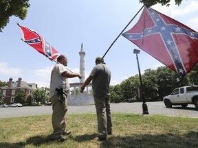 FILE - In this Thursday, June 25, 2015 file photo, activists hold Confederate flags near the monument for Confederate President Jefferson Davis on Monument Avenue in Richmond, Va. The monument was vandalized the previous night, spray-painted with the phrase "Black Lives Matter," after a deadly mass shooting at a Charleston, S.C. predominantly-black church sparked a nationwide debate on the public display of Confederate imagery.