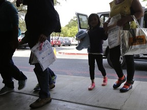 FILE - In this Monday, July 23, 2018 file photo, immigrants seeking asylum, some wearing ankle monitors, arrive at a Catholic Charities facility not long after they were reunited in San Antonio. Federal authorities' shift away from separating immigrant families caught in the U.S. illegally now means that many parents and children are quickly released, only to be fitted with electronic monitoring devices _ a practice which both the government and advocacy groups oppose for different reasons.