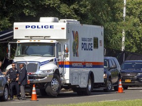 In this Tuesday, Aug. 28, 2018, photo, Nassau County Police conduct a search in a wooded area in East Meadow, N.Y., after the remains of a young man were discovered in a shallow grave nearby. Newsday has reported that, according to the Nassau County Police Commissioner, the man was killed by the MS-13 street gang.
