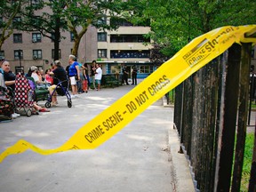 In this July 18, 2018 photo, a broken crime scene tape blows in the wind as Bushwick Houses neighbors gather and police stand near the site where15-year-old resident Kyon Jackson was gunned down a day earlier in the Brooklyn borough of New York. New York City is enlisting former gang members as "violence interrupters" to help keep the peace amid a summer uptick in the killings of young people.