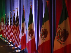 FILE - In this Aug. 16, 2017 file photo, the national flags of Canada, from left, the U.S. and Mexico, are lit by stage lights before a news conference, at the start of North American Free Trade Agreement renegotiations in Washington. President Donald Trump says the prospects are "looking good" for an agreement with Mexico that could set the stage for an overhaul of the NAFTA. "A big deal looking good with Mexico!" Trump tweeted Monday, Aug. 27.