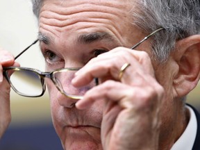 FILE- In this July 18, 2018, file photo Federal Reserve Board Chair Jerome Powell put on his glasses while testifying during a House Committee on Financial Services hearing on Capitol Hill in Washington. Powell gives the keynote address Friday, Aug. 24, at an annual conference of central bankers in Jackson Hole, Wyo.
