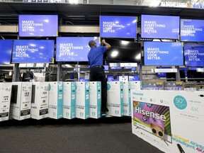 FILE- In this May 23, 2017, file photo, an employee adjusts a television display at a Best Buy in Cary, N.C. Many kinds of old-guard chains have posted strong sales, both online and at stores, and are raising their outlooks for the year.