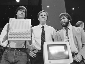 FILE - In this April 24, 1984 file photo, Steve Jobs, left, chairman of Apple Computers, John Sculley, center, president and CEO, and Steve Wozniak, co-founder of Apple, unveil the new Apple IIc computer in San Francisco, Calif.  Apple has become the world's first company to be valued at $1 trillion, the financial fruit of tasteful technology that has redefined society since two mavericks named Steve started the company 42 years ago.