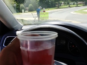 CORRECTS TO A BOY, NOT A TEENAGER - This Saturday, Aug. 4 2018, photo provided by James Castellano, of Monroe, N.C., shows a drink he bought from a boy, background, in Monroe. A teenager who held up the North Carolina lemonade stand for $17 was still at large Monday, Aug. 6, and authorities said they hoped to track him through surveillance footage and possible DNA and fingerprint tests.
