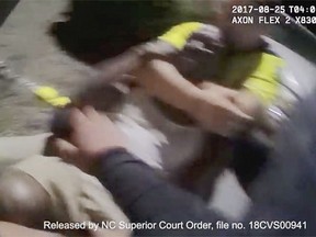 FILE - In this Aug. 25, 2017, file image made from video released by the Asheville, (N.C.) Police Department, Johnnie Jermaine Rush grimaces after officer Christopher Hickman overpowers Rush in a chokehold in Asheville, N.C. Hickman, a white North Carolina officer charged with beating a black pedestrian, had a history of "harmful" behavior caught on body camera, according to an external review presented to the City Council on Tuesday, Aug. 28, 2018, that urged thorough audits of police footage to catch behavior problems sooner. (Asheville Police Department via AP, File)