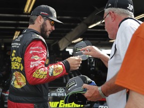 NASCAR Cup Series auto race driver Martin Truex Jr., left, signs an autograph for a fan before a practice session, Saturday, Aug. 4, 2018, in Watkins Glen, N.Y.