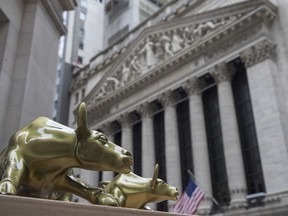 FILE- In this April 24, 2018, file photo replicas of Arturo Di Modica's "Charging Bull" are for sale on a street vendor's table outside the New York Stock Exchange in New York. The U.S. stock market opens at 9:30 a.m. EDT on Friday, Aug 17.