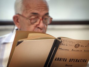 FILE - In this July 29, 2009, file photo, a man who refused to be identified by name reads a communist era secret police file at the headquarters of the National Council for the Study of Securitate Archives in Bucharest, Romania. Some 70 informants and spies secretly recorded the life of Katherine Verdery, now an Anthropology Professor at the University of New York, when she worked periodically as an anthropology graduate in Communist Romania.