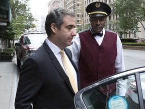 Michael Cohen, left, former personal lawyer to President Donald Trump, leaves his apartment building past his doorman, in New York, Tuesday, Aug. 21, 2018. Cohen could be charged before the end of the month with bank fraud in his dealings with the taxi industry and with committing other financial crimes, multiple people familiar with the federal probe said Monday.