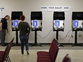 FILE - In this Thursday, Oct. 19, 2017, file photo, Kelly Monroe, investigator with the Georgia Secretary of State office, left, takes a look at a new voting machine that produces a paper record being tested at a polling site in Conyers, Ga. States have quickly tapped into $380 million from the federal government to help them shore up their election systems. A report released Tuesday, Aug. 21, 2018, by the U.S. Election Assistance Commission says the largest chunk will be used to improve cybersecurity in 41 states and territories. More than a quarter of the money will go to buy new voting equipment.