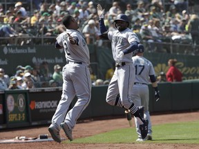 Seattle Mariners' Dee Gordon, right, celebrates with Jean Segura after hitting a two-run home run that scored Mike Zunino against the Oakland Athletics during the 12th inning of a baseball game in Oakland, Calif., Wednesday, Aug. 15, 2018.