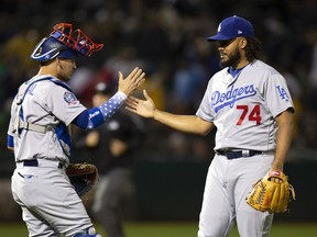Los Angeles Dodgers catcher Yasmani Grandal (9) and pitcher Kenley Jansen (74) celebrate the team's 4-2 victory over the Oakland Athletics in a baseball game, Tuesday, Aug. 7, 2018, in Oakland, Calif.