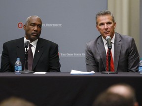 Ohio State football coach Urban Meyer, right, answers questions as athletic director Gene Smith listens during a news conference in Columbus, Ohio, Wednesday, Aug. 22, 2018. Ohio State suspended Meyer on Wednesday for three games for mishandling domestic violence accusations, punishing one of the sport's most prominent leaders for keeping an assistant on staff for several years after the coach's wife accused him of abuse. Athletic director Smith was suspended from Aug. 31 through Sept. 16.