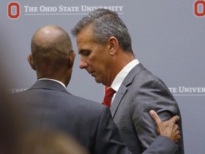 Ohio State University President Michael Drake offers words to football coach Urban Meyer, who leaves the stage following a news conference in Columbus, Ohio, Wednesday, Aug. 22, 2018. Ohio State suspended Meyer on Wednesday for three games for mishandling domestic violence accusations, punishing one of the sport's most prominent leaders for keeping an assistant on staff for several years after the coach's wife accused him of abuse. Athletic director Gene Smith was suspended from Aug. 31 through Sept. 16.