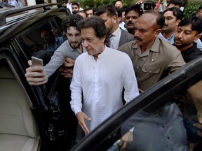 A man takes a selfie with Imran Khan, centre, head of the Pakistan Tehreek-e-Insaf party, as he leaves a party meeting in Islamabad, Pakistan, Monday, Aug. 6, 2018.