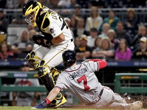 Pittsburgh Pirates catcher Francisco Cervelli, left, forces out Atlanta Braves' Dansby Swanson (7) on a bases-loaded grounder by Ender Inciarte during the eighth inning of a baseball game, Wednesday, Aug. 22, 2018, in Pittsburgh.