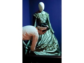 In this photo made on Thursday, Aug. 23, 2018, Jean-Luc Deladurantaye adjusts one of the dresses while helping to install an exhibit of Ruth E. Carter cinematic costumes at Pittsburgh's Senator John Heinz History Center in Pittsburgh. The exhibit that opens Saturday, Aug. 25, explores Carter's groundbreaking career. "Heroes & Sheroes: The Art and Influence of Ruth E. Carter in Black Cinema" showcases over 40 costumes from nine movies. The costumes include those from "Amistad," "What's Love Got to do With It," "The Butler," "Malcolm X," "Selma," "Do the Right Thing" and of course "Black Panther." It is scheduled to run to Dec. 2, 2018.