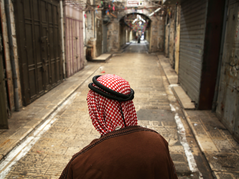 A Palestinian man wearing Keffiyeh walks at a street in the West