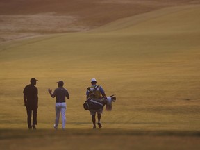 Tiger Woods, Rory McIlroy, of Northern Ireland, and caddie Harry Diamond, from left, walk out to the course to resume the second round of the PGA Championship golf tournament at Bellerive Country Club, Saturday, Aug. 11, 2018, in St. Louis.