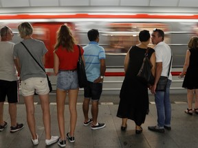 Passengers stand on a platform as a subway train arrives at a station in Prague, Czech Republic, Tuesday, Aug. 7, 2018. Two participants in a travel competition "LowCost Race" were allowed by a driver to drive a subway train with passengers in the Czech capital after the race started on Aug 3.