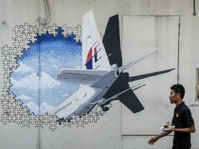 In this Tuesday, Feb. 23, 2016 photo, a waiter walks past a mural of flight MH370 in Shah Alam outside Kuala Lumpur, Malaysia. Relatives of Chinese passengers who were aboard missing Malaysia Airlines Flight 370 said Friday they refuse to accept the latest report on the plane’s disappearance four years ago and demand the search be restarted.