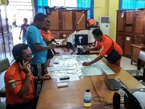 A handout photo taken on August 11, 2018 and released by the Indonesian National Search and Rescue Agency shows officers trying to locate a Swiss-made Pilatus aircraft, at their office in Jayapura, in Papua province on August 11, 2018 after it lost contact with air traffic control.