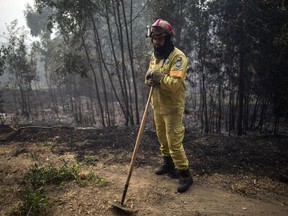 A firefighter takes a break outside the village of Monchique, in southern Portugal's Algarve region, Monday, Aug. 6, 2018. Emergency services in Portugal say they are still fighting a major wildfire on the south coast that threatened to engulf a hillside town overnight.