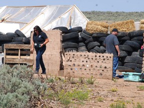 CORRECTS BYLINE TO MORGAN LEE INSTEAD OF LEE MORGAN - Taos County Planning Department officials Rachel Romero, left, and Eric Montoya survey property conditions at a disheveled living compound at Amalia, N.M., on Tuesday, Aug. 7, 2018. A New Mexico sheriff said searchers have found the remains of a boy at the makeshift compound that was raided in search of a missing Georgia child.