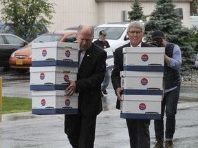 Alaska Gov. Bill Walker, left, and Lt. Gov. Byron Mallott carry boxes into the Division of Elections office in Anchorage, Alaska, Monday, Aug. 20, 2018, after the two men gathered signatures to get their ticket on the November general election ballot. Walker is an independent and Mallott is a Democrat, and they decided to gather signatures to advance to the November election instead of taking part in the primary election on Aug. 21.