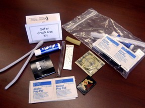 A safe crack use kit is shown, with four alcahol swabs, one condom, one piece of chewing gum, a tube of Lypsyl,  one book of matches, a pipe cleaner and a modular crack pipe consisting of a glass tube, a short length of rubber and a pack of five pipe screens.