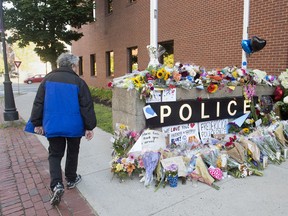 aramedic Brian Fournier walks away after playing a hymn and placing a tribute at the police station in Fredericton on Friday, Aug. 10, 2018. Two city police officers were among four people who died in a shooting in a residential area on the city's north side.