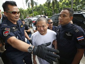 In this Thursday, July 20, 2017, file photo, ex-monk Wirapol Sukphol is escorted by the Department of Special Investigation officials to the prosecutor's office in Bangkok, Thailand. Wirapol, a former monk known for a jet-setting lifestyle has been sentenced to over a hundred years in prison for deceiving his followers into making costly donations and embezzling the money.