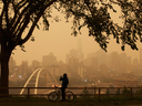 A morning commuter stops to take a photo of the city as smoke from the B.C. wildfires rolls in over Edmonton on Aug. 15, 2018.