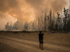 A man photographs a wildfire burning approximately 20km southwest of Fort St. James, B.C., on Aug. 15, 2018.