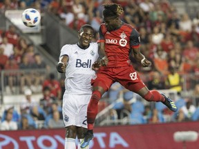 Toronto FC's Tosaint Ricketts, right, rises above Vancouver Whitecaps' Doneil Henry to score his team's fifth goal during second half action in the Canadian Championship final's second leg in Toronto on Wednesday night.