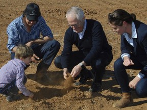 In this June 4, 2018, photo, Australian Prime Minister Malcolm Turnbull, second right, looks at dry soil with farmers during a visit to Strathmore Farm near Trangie, 485 kilometres northwest of Sydney.