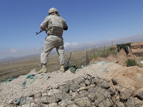 A Russian military police officer stands guard near the village of Tal Kroum, Syria, Tuesday, Aug. 14, 2018.