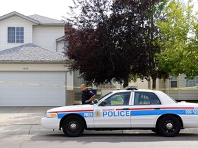 A Calgary Police officer guards a house in Calgary, Tuesday, July 31, 2018. Calgary police have a suspect in custody after finding three people dead at two different homes across the city.