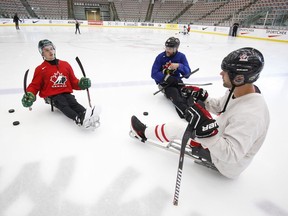 Ryan Straschnitzki, left to right, talks to former Calgary Flames' Brian McGrattan and his mentor Chris Cedarstrand on the ice as he practices his sledge hockey skills in Calgary on Tuesday, August 7, 2018. Straschnitzki was injured in the Humboldt Broncos bus crash.