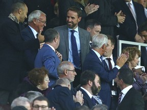 England soccer team manager Gareth Southgate, top center, and Claudio Ranieri, second left, take their seats for the English Premier League soccer match between Manchester United and Tottenham Hotspur at Old Trafford stadium in Manchester, England, Monday, Aug. 27, 2018.