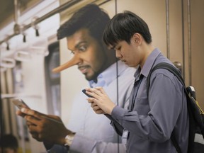 FILE - In this April 2, 2018, fie photo, a commuters walks past an advertisement discouraging the dissemination of fake news, at a train station in Kuala Lumpur, Malaysia. Malaysia's new government on Thursday, Aug. 16, 2018, repealed a widely criticized law prohibiting "fake news," in a move hailed as a landmark moment for human rights by a group of Southeast Asian lawmakers.